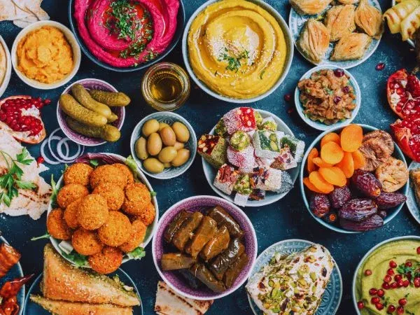 Table couverte de plats du monde : houmous, falafels, feuilles de vigne, grenade et mezzés